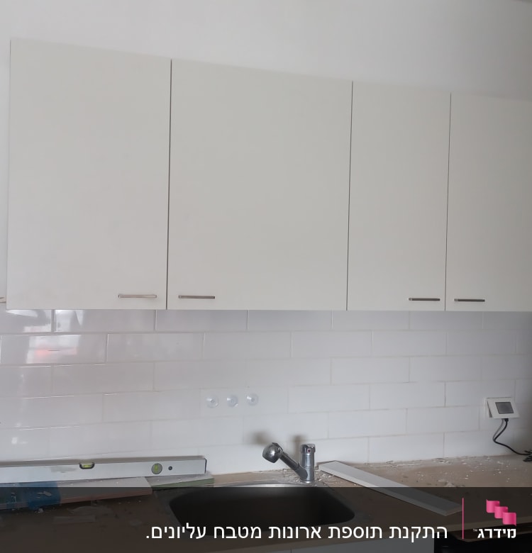 מטבח עם ארונות לבנים, כיור וברז מותקנים